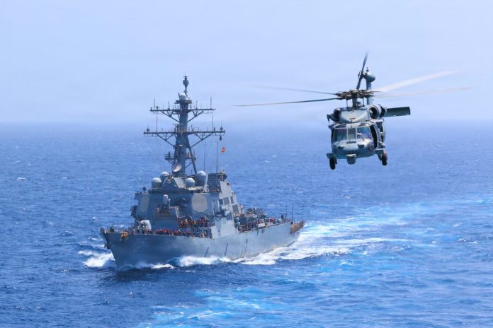 Есмінець USS Donald Cook (DDG 75) проходить Аравійським морем, а поруч виконує політ вертоліт MH-60S Sea Hawk. Фото: CENTCOM